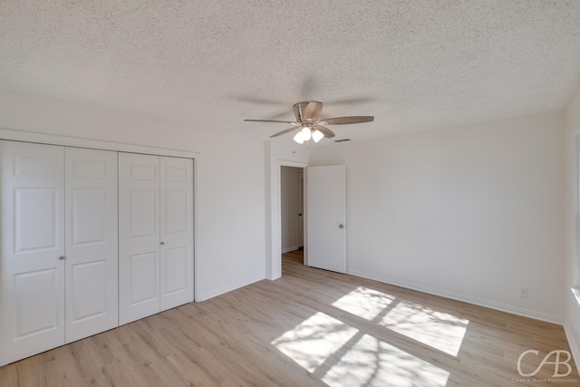 unfurnished bedroom with ceiling fan, light hardwood / wood-style floors, a closet, and a textured ceiling