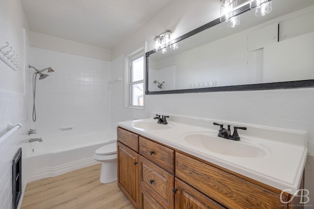 full bathroom with wood-type flooring, toilet, tiled shower / bath combo, and vanity