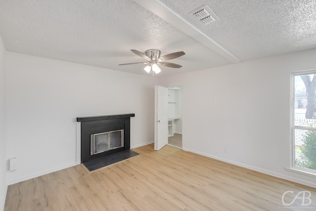 unfurnished living room featuring ceiling fan, light hardwood / wood-style flooring, plenty of natural light, and a textured ceiling