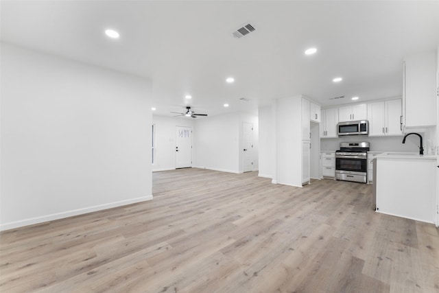 unfurnished living room with sink, ceiling fan, and light hardwood / wood-style flooring