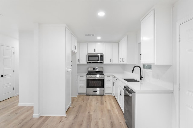 kitchen featuring appliances with stainless steel finishes, light countertops, a sink, and visible vents