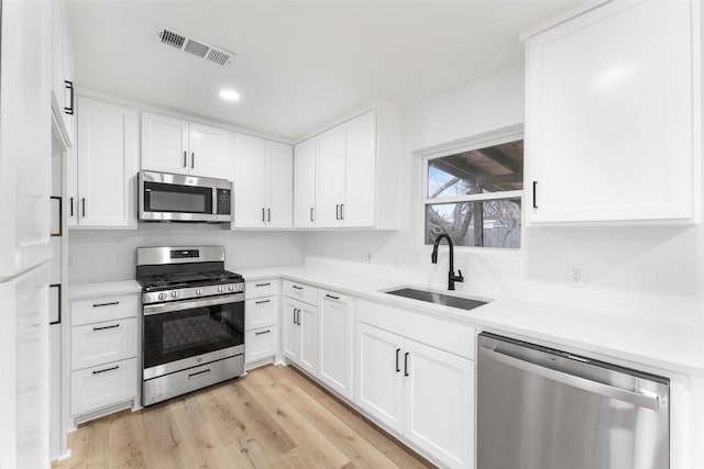 kitchen with light countertops, appliances with stainless steel finishes, visible vents, and white cabinetry