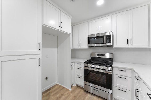 kitchen featuring light wood finished floors, decorative backsplash, light stone countertops, stainless steel appliances, and white cabinetry