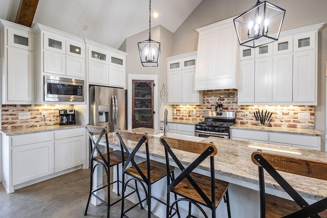 kitchen with vaulted ceiling, hanging light fixtures, decorative backsplash, white cabinets, and stainless steel appliances