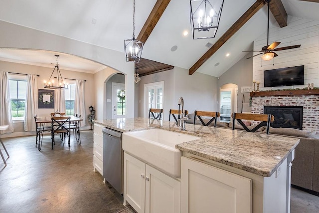 kitchen featuring stainless steel dishwasher, pendant lighting, white cabinetry, high vaulted ceiling, and an island with sink