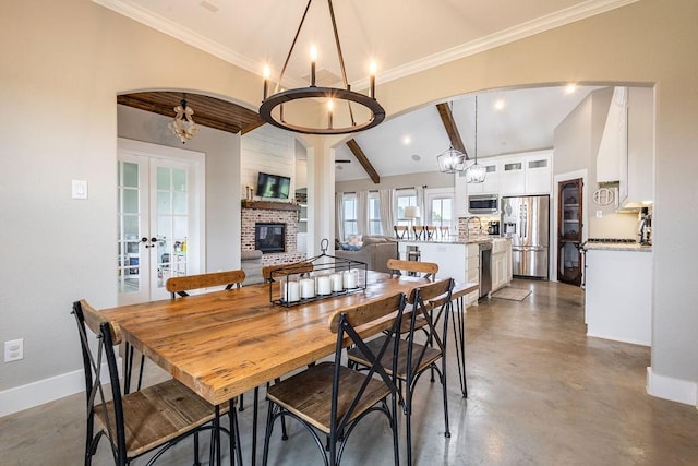 dining area with a notable chandelier, french doors, a brick fireplace, and lofted ceiling with beams