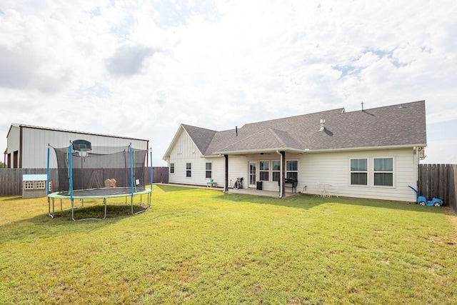 rear view of house with a trampoline, a yard, and a patio area