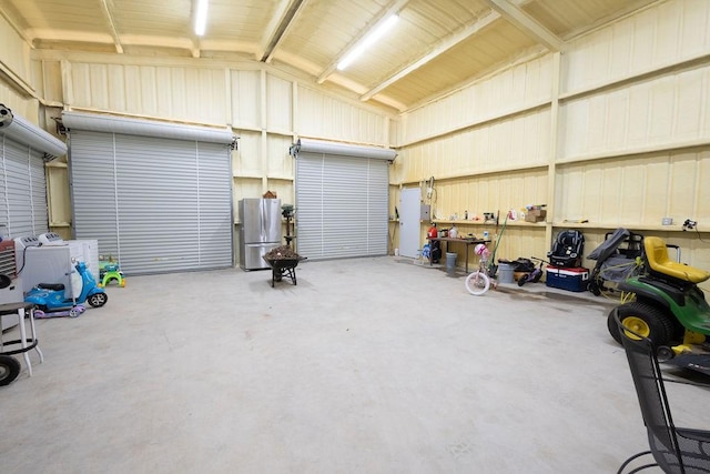 garage with washing machine and dryer and stainless steel fridge