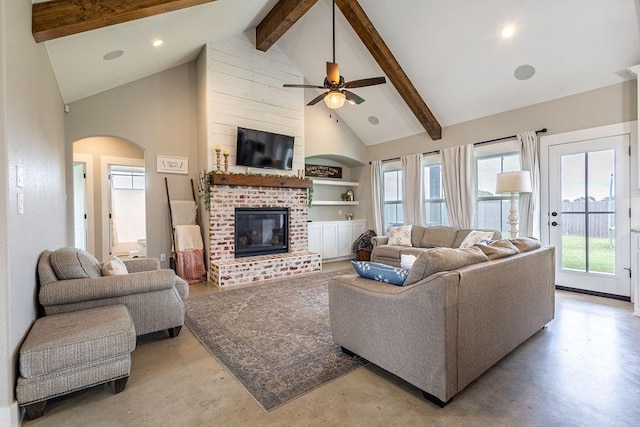 living room featuring built in shelves, a fireplace, ceiling fan, high vaulted ceiling, and beam ceiling