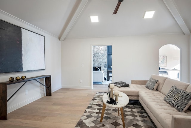 living room featuring ceiling fan, ornamental molding, lofted ceiling with beams, and light wood-type flooring