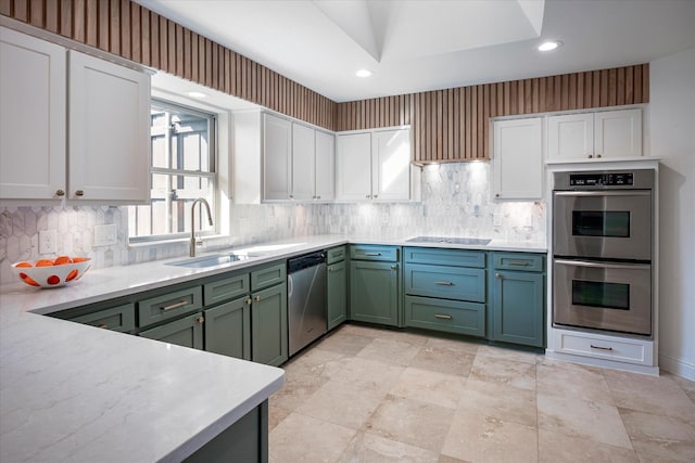 kitchen featuring lofted ceiling, sink, white cabinets, green cabinets, and stainless steel appliances