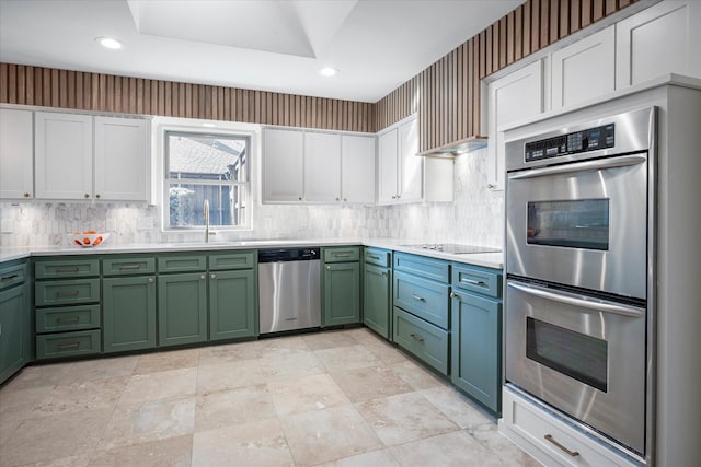 kitchen with sink, green cabinets, white cabinetry, backsplash, and stainless steel appliances