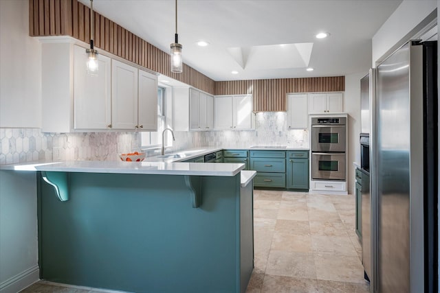 kitchen featuring hanging light fixtures, stainless steel appliances, white cabinets, a kitchen bar, and kitchen peninsula