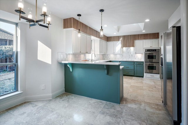 kitchen with white cabinetry, appliances with stainless steel finishes, a healthy amount of sunlight, and decorative light fixtures