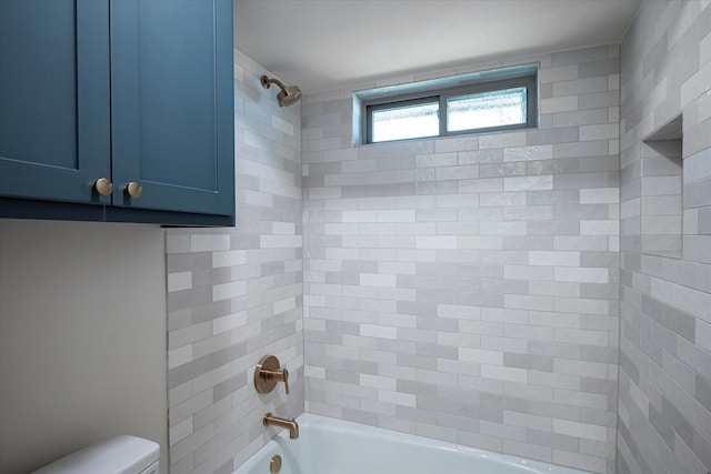 bathroom with tiled shower / bath combo and toilet