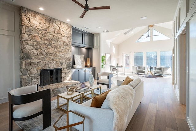 living room with lofted ceiling, hardwood / wood-style floors, a fireplace, and ceiling fan