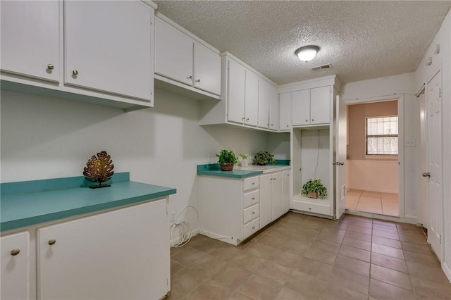 kitchen with white cabinets, light tile patterned floors, and a textured ceiling