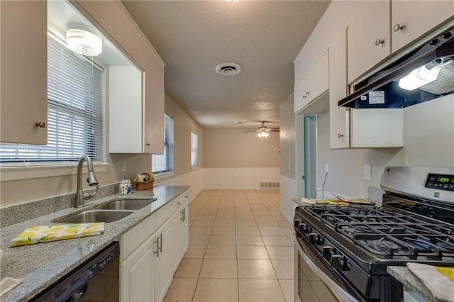 kitchen with stainless steel gas stove, sink, white cabinets, light tile patterned floors, and light stone counters