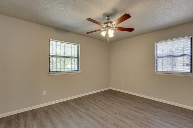 empty room with a wealth of natural light, a textured ceiling, and wood-type flooring