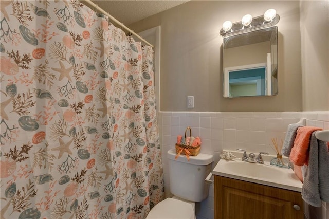 bathroom featuring toilet, a textured ceiling, walk in shower, tile walls, and vanity