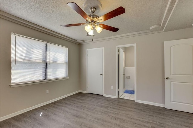 unfurnished bedroom with ceiling fan, light hardwood / wood-style floors, a textured ceiling, and ensuite bath