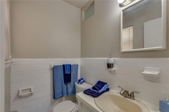 bathroom with sink, toilet, and tile walls