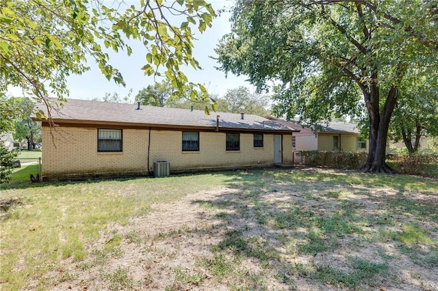 rear view of house with cooling unit and a lawn