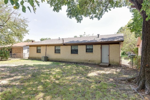 rear view of house featuring central AC unit and a lawn