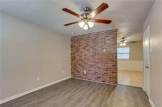 unfurnished room featuring ceiling fan, brick wall, dark wood-type flooring, and a textured ceiling