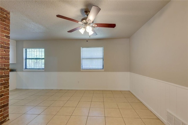 spare room with light tile patterned flooring, a textured ceiling, and ceiling fan