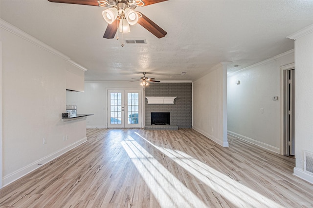 unfurnished living room featuring french doors, a fireplace, ceiling fan, light hardwood / wood-style flooring, and crown molding