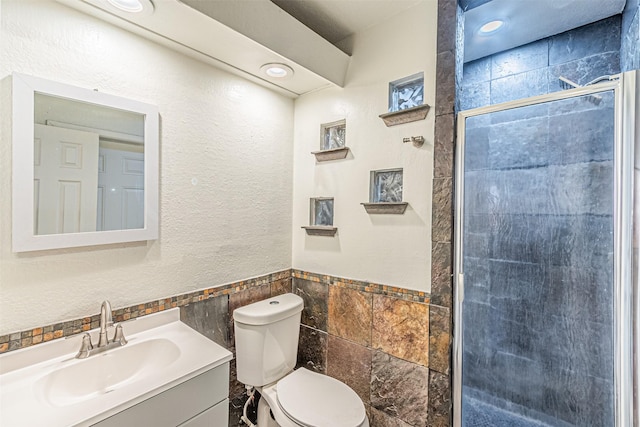 bathroom with tile walls, toilet, walk in shower, and vanity