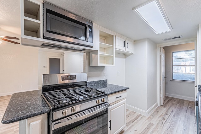 kitchen featuring appliances with stainless steel finishes, a textured ceiling, white cabinetry, light wood-type flooring, and ceiling fan