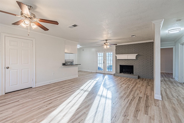 unfurnished living room with a fireplace, a textured ceiling, light wood-type flooring, ornamental molding, and ceiling fan