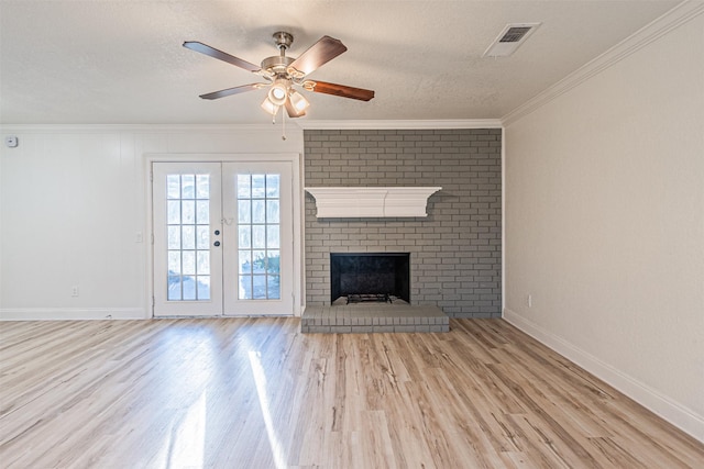 unfurnished living room with light hardwood / wood-style floors, a fireplace, a textured ceiling, french doors, and ornamental molding