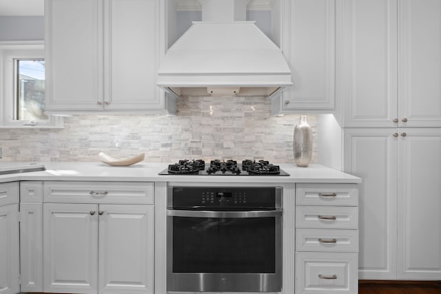 kitchen featuring stainless steel oven, white cabinetry, gas stovetop, and custom range hood