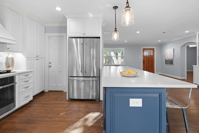 kitchen featuring white cabinets, a kitchen island, decorative light fixtures, stainless steel appliances, and crown molding