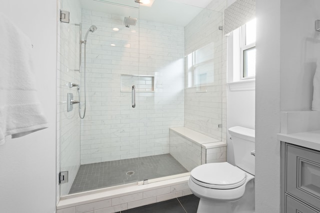 bathroom with a shower with shower door, tile patterned floors, vanity, and toilet