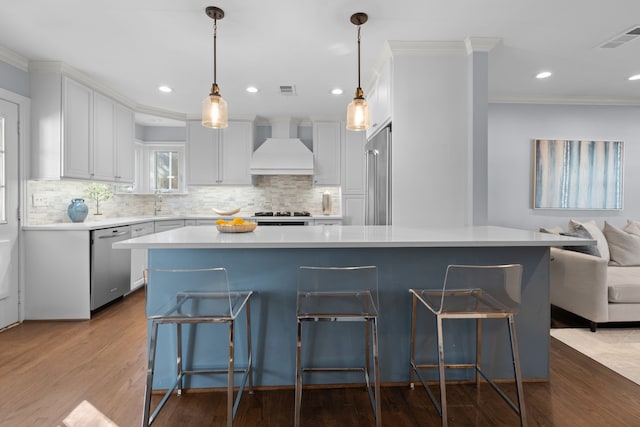 kitchen featuring white cabinets, custom exhaust hood, decorative light fixtures, a large island, and stainless steel dishwasher