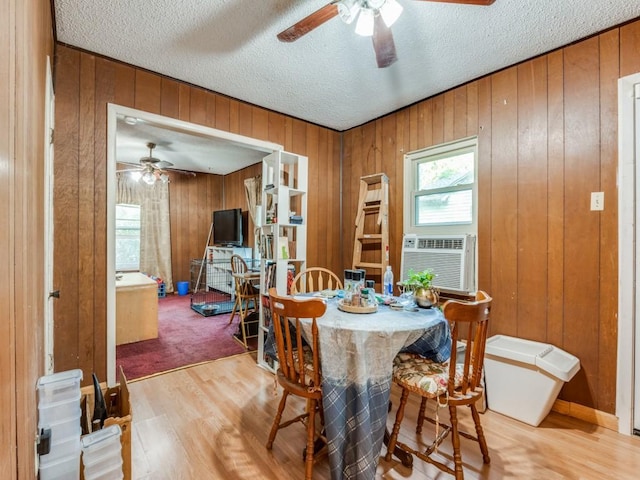 dining room with wood walls, hardwood / wood-style floors, and a textured ceiling