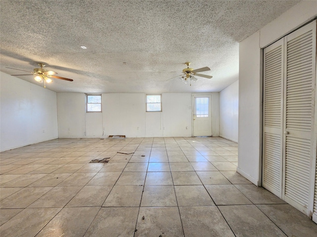 tiled spare room with a textured ceiling and ceiling fan