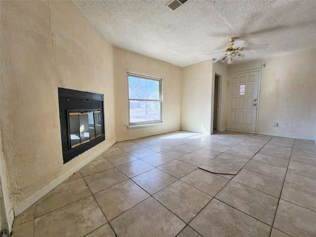 unfurnished living room with ceiling fan and a textured ceiling