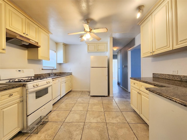 kitchen featuring cream cabinets, white appliances, light tile patterned floors, sink, and dark stone counters