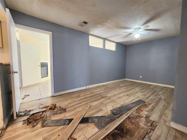 empty room with light hardwood / wood-style floors, a textured ceiling, and ceiling fan