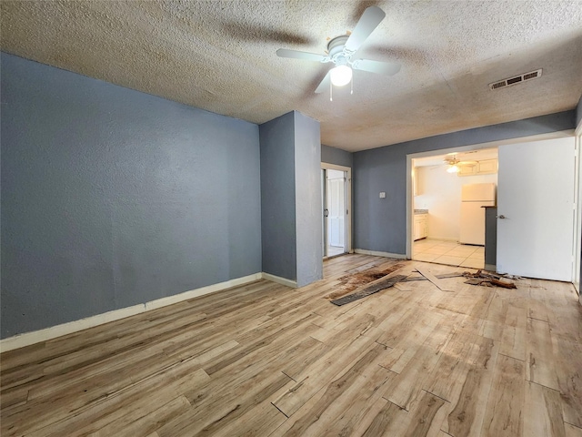 spare room featuring ceiling fan, light hardwood / wood-style flooring, and a textured ceiling