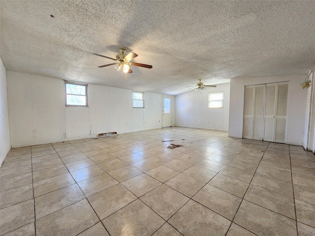 tiled spare room with a textured ceiling, vaulted ceiling, and ceiling fan