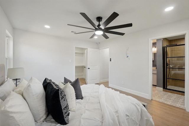 bedroom featuring light hardwood / wood-style floors, ceiling fan, and a walk in closet