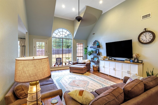 living room with a towering ceiling, crown molding, and light hardwood / wood-style floors