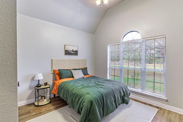 bedroom with wood-type flooring, multiple windows, ceiling fan, and vaulted ceiling