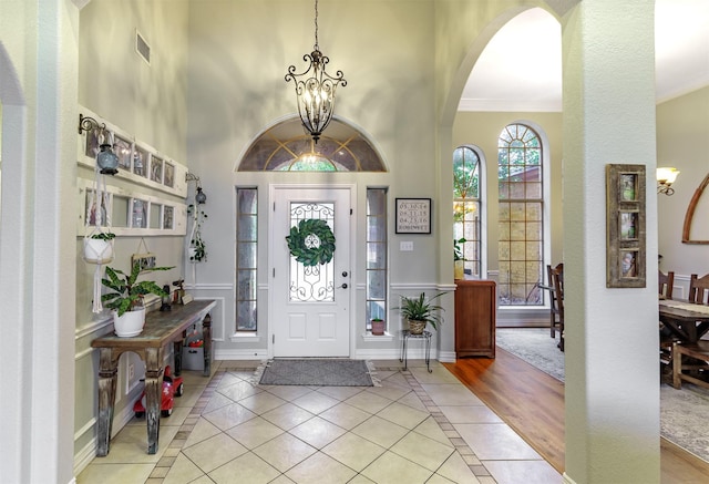 foyer entrance with crown molding, light tile patterned flooring, and a chandelier